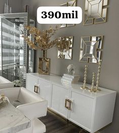 a living room filled with white furniture and gold accents on top of each piece of furniture