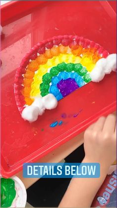 a child is painting a rainbow cake with white icing on the top and bottom