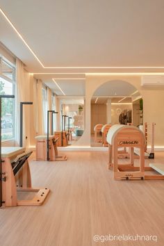 an empty gym with wooden benches and exercise equipment in the foreground is a large window