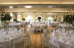 a room filled with lots of tables covered in white clothed tablecloths and centerpieces