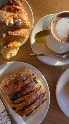 two white plates topped with pastries next to a cup of coffee