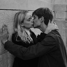 a man and woman kissing against a wall