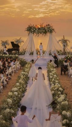 the bride is walking down the aisle with her dress flowing in front of her and groom