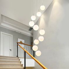 the light fixture is hanging from the ceiling above the stairs in this modern house with white walls and wood flooring