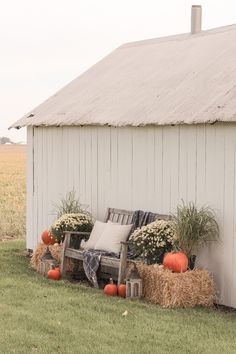 a white barn with hay bales and pumpkins