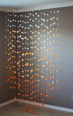 a room with a wall hanging made out of orange and white paper leaves on it