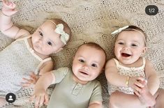 three babies are laying on the floor and smiling