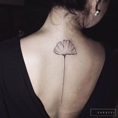 the back of a woman's neck with a single flower tattoo on it