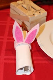 a napkin holder with bunny ears on it sitting next to a plate and some forks