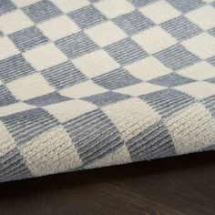 a close up view of a blue and white checkered blanket on a wooden floor