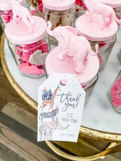 pink elephants and giraffes are on display in glass jars with thank you tags