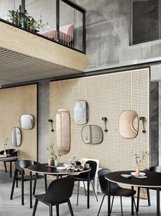 an empty restaurant with tables and chairs in front of a wall decorated with mirrors, plants and potted plants