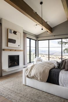 a large bed sitting in the middle of a bedroom next to a fireplace and windows