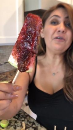 a woman holding up a piece of meat on a stick