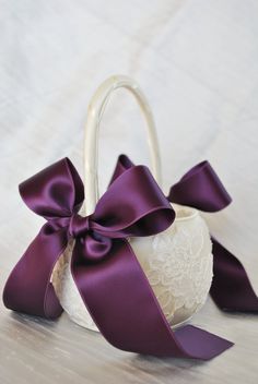 a flower girl basket with purple satin ribbons