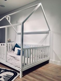 a white bed with a canopy over it in a room that has hardwood floors and walls