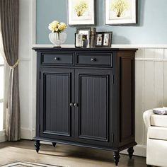 a black cabinet with two pictures above it in a living room next to a white couch