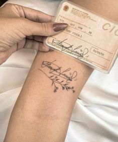 a woman's arm with a tattoo on it and a check card in her other hand