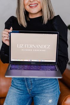 a woman holding up a laptop computer with the name liz fernanddz on it