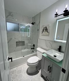 a white toilet sitting next to a walk in shower under a bathroom mirror above a sink