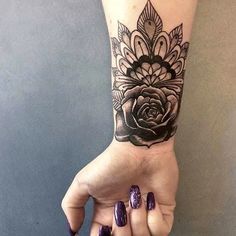 a woman's hand with a black and white rose tattoo on the left wrist