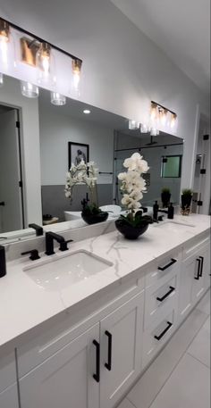 a large bathroom with two sinks, mirrors and flowers in vases on the counter