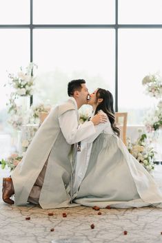 a bride and groom kissing on the floor in front of large windows at their wedding