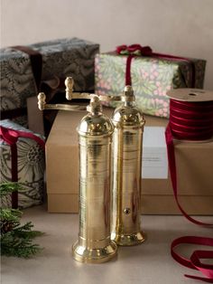 two golden pepper shakers sitting on top of a table next to boxes and presents