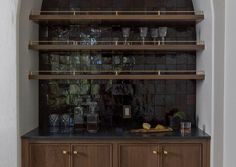 Moody dark tile backsplash adds a bit of drama to this built in bar space.