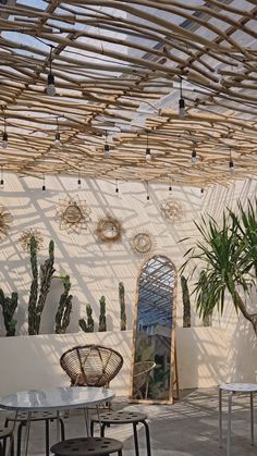 the interior of a restaurant with tables and chairs in front of a white wall that has plants on it