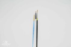 two chopsticks are sitting next to each other on a white surface, one has blue and the other is black