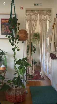 a living room with plants and rugs hanging from the ceiling in front of it