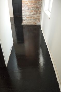 an empty room with black floor and brick wall