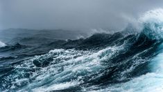 a large wave in the ocean on a cloudy day