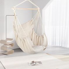 a white hammock hanging from the ceiling in a living room next to a window