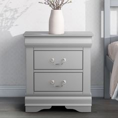 a white vase sitting on top of a gray dresser next to a bed and nightstand