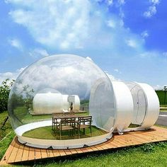 an inflatable bubble tent is set up on a wooden platform near a picnic table