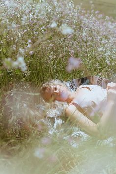 a woman laying in the grass with her eyes closed