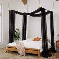 a canopy bed with black drapes and pillows