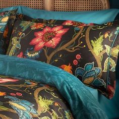 the comforter is made up with colorful flowers and birds on black, teal, and blue