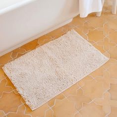 a white bath mat sitting on top of a bathroom floor