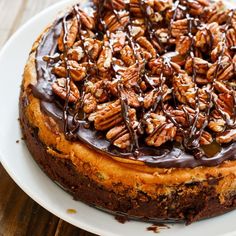 a cake with chocolate frosting and pecans on top sitting on a white plate