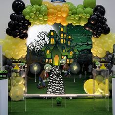 an entrance to a halloween themed party with black, yellow and green balloons in the shape of houses