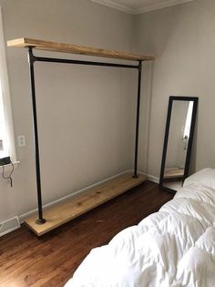 a bed sitting in a bedroom next to a mirror on top of a wooden floor