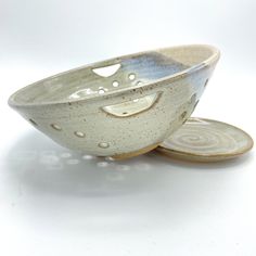 two ceramic bowls with holes in them on a white surface