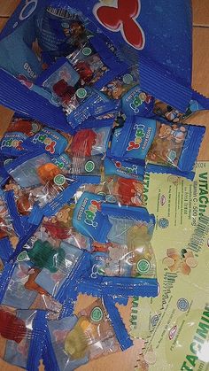 several bags of gummy bears on the floor next to a bag of candy chips