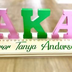 the letters are made out of wood and have green, pink, and purple letters