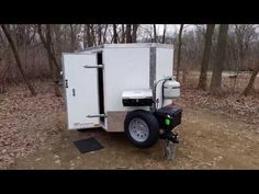 a small white trailer parked in the woods