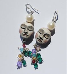 a pair of earrings with faces and beads hanging from it's earwires