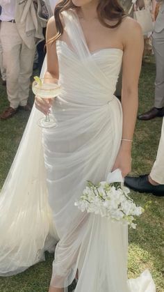 a woman in a white dress is holding a bouquet and posing for the camera with other people around her